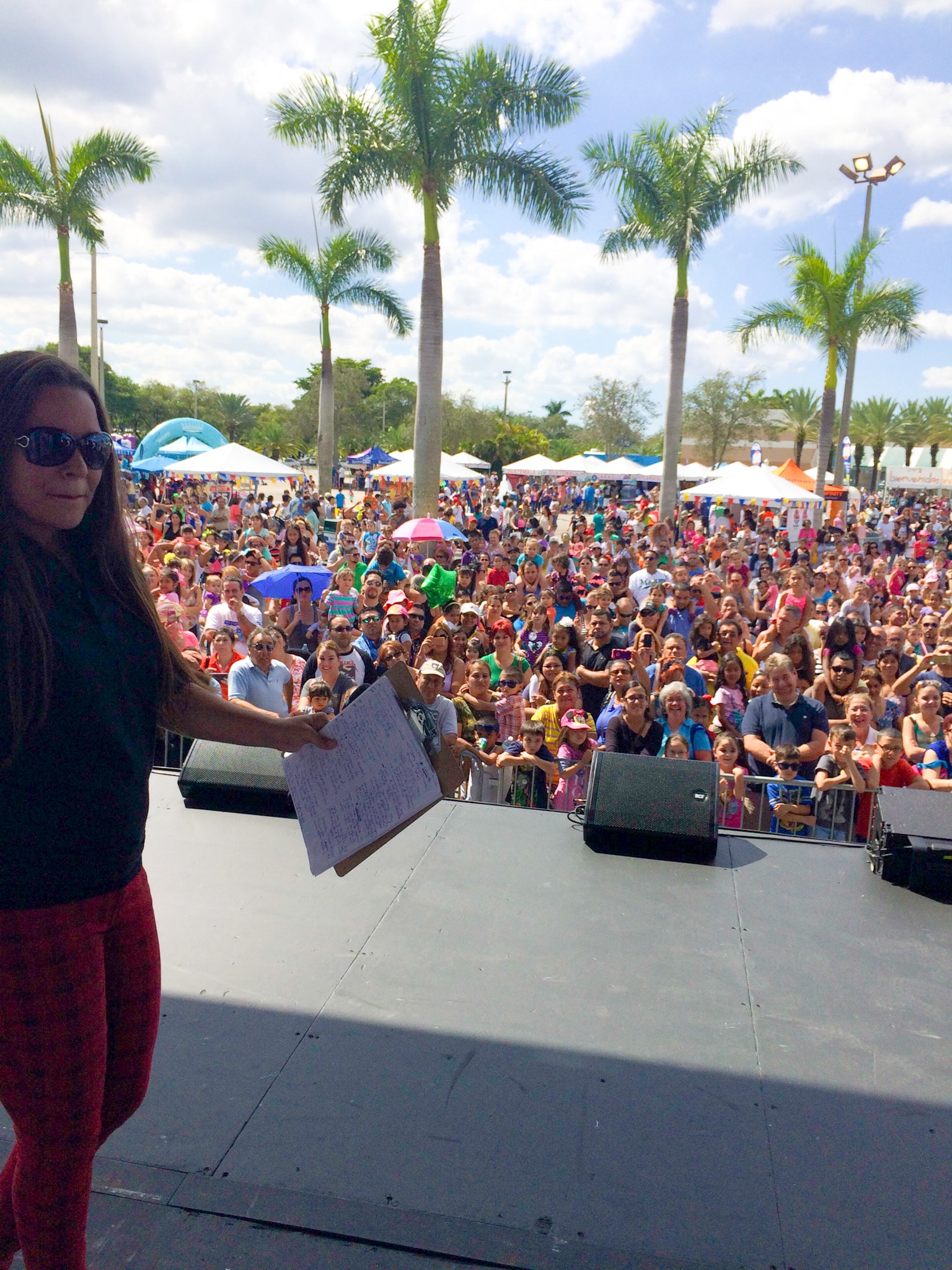 GiGi Diaz on stage addressing a large outdoor crowd